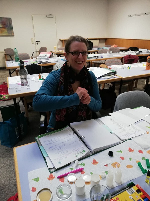 Frau sitzt in einem Seminar beim Tisch und mischt ätherische Öle.